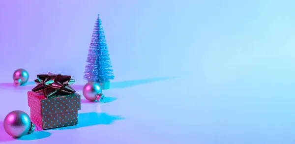 圣诞作曲霓虹灯 在霓虹灯坡度背景上的假日装饰球 最小的抽象树 圣诞礼物盒 新年大旗 — 图库照片
