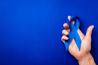 Prostat bakımı. Kasım ayında erkek sağlığının prostat kanseri olduğunun farkındalığı. Mavi kurdele, derin mavi arka planda izole edilmiş ellerde. Dünya Kanser Günü ve Dünya Diyabet Günü Konsepti