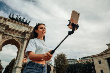 Gezginler Milan adasını etkiliyor. Avrupa 'da boyama evi Milano' da. Piazza del Duomo, Katedral Meydanı 'nda akıllı telefonlu fotoğrafçı kız. Seyahat ve serbest çalışma, modern yaşam tarzı.