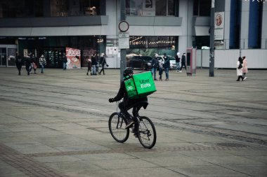 KATOWICE. POLAND - 26 Mart 2021: teslimat servisi için yemek çantası. Hızlı restoran teslimatı için bisikletli ya da motosikletli adam. Uber ekspres gıda dağıtım servisi yiyor