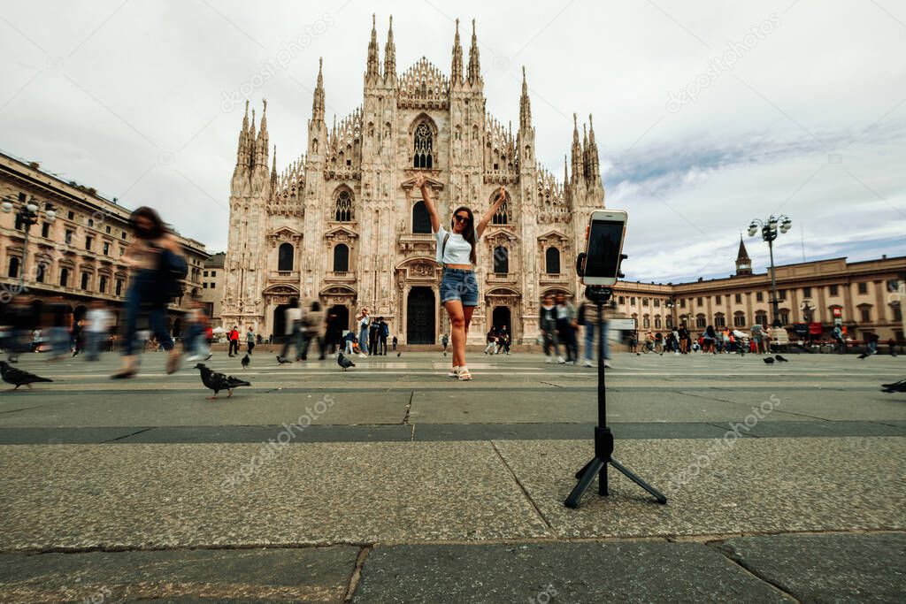 Influence media Milan Italy. Paint building house in Europe Milano city. Travel photographer blogger girl with smartphone in Piazza del Duomo. Freedom, summer travel, profession concept