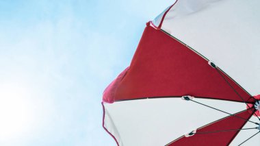 Şemsiye plajı. Mavi deniz arka planında kızıl yaz plajı şemsiyesi. Tatil için güneş kremi. Açık hava tatilini okyanusta fotokopi alanı ile rahatlat