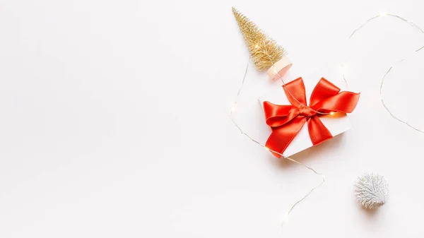 冬天的横幅白色礼物 红色蝴蝶结 金球和闪光的灯饰圣诞装饰白色背景的贺卡 平面布局 顶视图 复制空间 — 图库照片