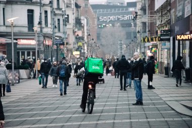 KATOWICE. POLAND - 26 Mart 2021: teslimat servisi için yemek çantası. Hızlı restoran teslimatı için bisikletli ya da motosikletli adam. Uber ekspres gıda dağıtım servisi yiyor