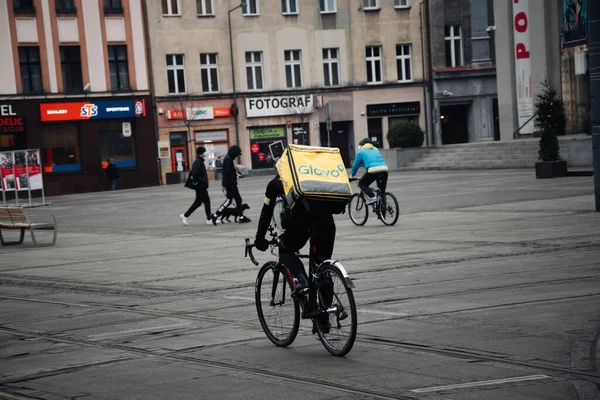 KATOWICE. POLAND - 26 Mart 2021: hızlı restoran teslimatı için bisikletli ya da motosikletli adam. Paket servisi için yemek paketi. Glovo kuryesi scooter 'da yemek getiriyor.