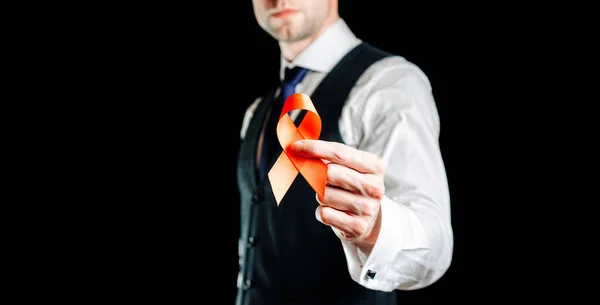 Aides au VIH. Ruban rouge en hiv journée mondiale isolé sur fond sombre. Homme tenant des aides de sensibilisation et symbole de cancer. Santé, signe médical. espace de copie. — Photo