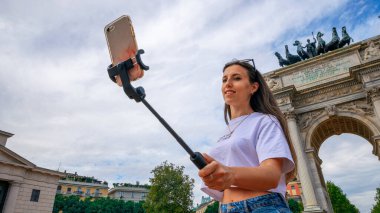 Gezginler Milan adasını etkiliyor. Avrupa 'da boyama evi Milano' da. Piazza del Duomo, Katedral Meydanı 'nda akıllı telefonlu fotoğrafçı kız. Seyahat ve serbest çalışma, modern yaşam tarzı.