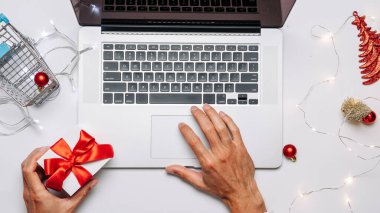 Tatil çevrimiçi alışveriş. Hediye kutusu kırmızı kurdele, tramvay ve dizüstü bilgisayar, düz konumda internet alışveriş kompozisyonu. Mutlu Noeller ve mutlu yıllar.