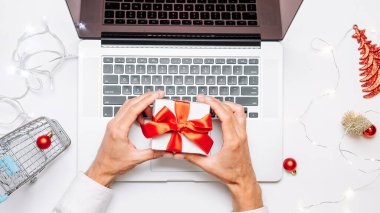 İnternetten noel alışverişi. Hediye kutusu kırmızı kurdele, tramvay ve dizüstü bilgisayar, düz konumda internet alışveriş kompozisyonu. Kış Xmas tatil satışları