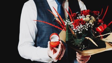 Evlilik teklifi. Elmas nişan yüzüğü, genç ve mutlu ellerde kırmızı güller. Sevgililer Günü 'nde elmas yüzük teklifi