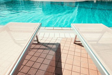 Tatil havuzu. Yaz tatili koltuğu, lüks otel havuzunda dinlenme salonu. Plaj şezlongu. Tatil yatağı. Mavi su, güneşli seyahat tatili