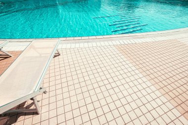 Güneş Salonu. Yaz tatili koltuğu, lüks otel havuzunda dinlenme salonu. Plaj şezlongu. Tatil yatağı. Mavi su, güneşli seyahat tatili