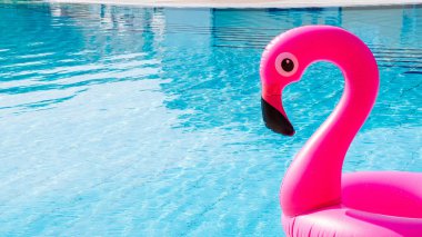 Flamingo plastiği. Plaj arka planı için havuz suyunda şişirilebilir pembe flamingo. Moda yaz konsepti