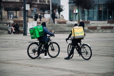 KATOWICE. POLAND - 26 Mart 2021: hızlı restoran teslimatı için bisikletli ya da motosikletli adam. Paket servisi için yemek paketi. Glovo kuryesi scooter 'da yemek getiriyor.