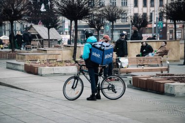 KATOWICE. POLAND - 26 Mart 2021: teslimat servisi için yemek çantası. Hızlı restoran teslimatı için bisikletli ya da motosikletli adam. Müşterilere hemen mal sevkiyatı yapın.