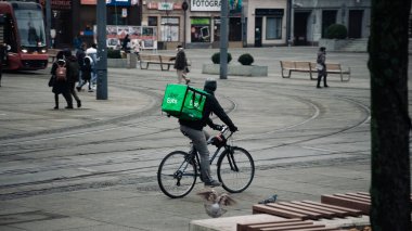 KATOWICE. POLAND - 26 Mart 2021: teslimat servisi için yemek çantası. Hızlı restoran teslimatı için bisikletli ya da motosikletli adam. Uber ekspres gıda dağıtım servisi yiyor