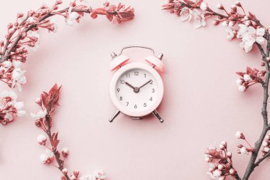 May flowers. Spring blossom and April floral nature with alarm clock on pink background. Beautiful scene with blooming tree. Easter Sunny day. Orchard abstract blurred background. Springtime