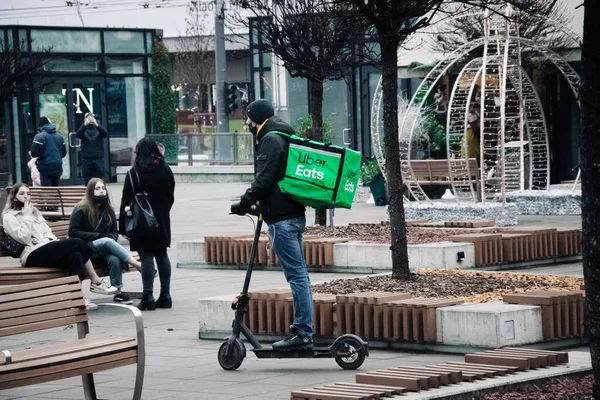 KATOWICE. POLAND - 26 Mart 2021: hızlı restoran teslimatı için bisikletli ya da motosikletli adam. Paket servisi için yemek paketi. Uber yemek dağıtırken mobiletle kurye yiyor.. — Stok fotoğraf