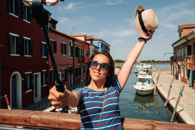 Medya Burano İtalya 'yı etkiler. Avrupa 'da Venezia şehrinde boyama evi. Venice Island Renk Sokağı 'nda akıllı telefonlu gezgin fotoğrafçı kız. Özgürlük, yaz seyahati, meslek kavramı