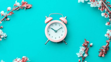 Yaz zamanı. Bahar çiçekleri ve çiçekli Nisan çiçekleri mavi arka planda çalar saat. Çiçek açan ağaçla güzel bir sahne. Paskalya güneşli bir gün. Meyve bahçesi arkaplanı bulanık. İlkbahar.