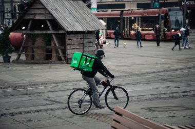 KATOWICE. POLAND - 26 Mart 2021: teslimat servisi için yemek çantası. Hızlı restoran teslimatı için bisikletli ya da motosikletli adam. Uber ekspres gıda dağıtım servisi yiyor