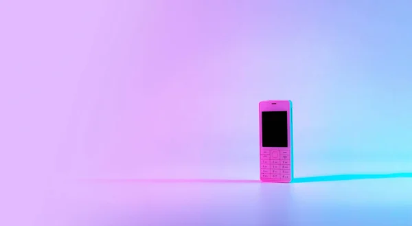 Retro cell phone vintage concept. White old mobile telephone in neon pink blue light. Retro wave. Pop art. minimal idea concept