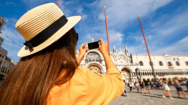 Seyahat etmenleri Venedik adasını etkiliyor. Avrupa 'da Venezia şehrinde boyama evi. Venice San Marco Meydanı 'nda akıllı telefonlu blogcu kız. Seyahat ve serbest çalışma, modern yaşam tarzı.