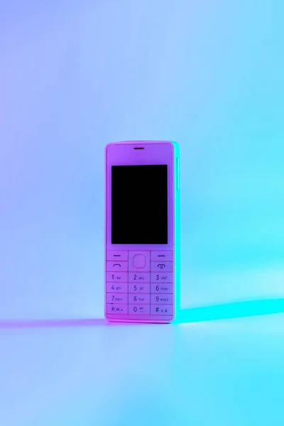 复古手机复古的概念 白色的旧手机上有霓虹灯粉红色的蓝光 复古波 流行艺术 最小概念概念 — 图库照片