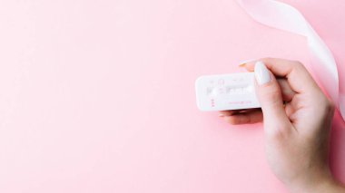 Hamilelik testi. Pembe arka planda pembe ipek kurdeleli hamile kadın testi. Yeni bir hayat ve yeni bir aile. Annelik, hamilelik, doğum kontrol kavramı