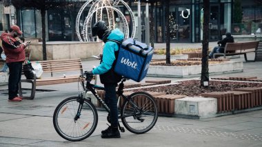 KATOWICE. POLAND - 26 Mart 2021: teslimat servisi için yemek çantası. Hızlı restoran teslimatı için bisikletli ya da motosikletli adam. Müşterilere hemen mal sevkiyatı yapın.