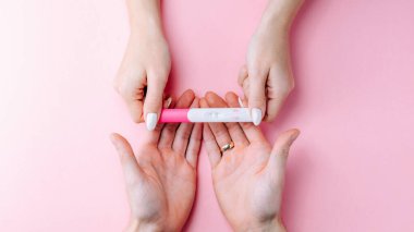 Hamilelik testi sonucu. Pembe arka planda pembe ipek kurdeleli hamile kadın testi. Yeni bir hayat ve yeni bir aile bayrağı. Annelik, hamilelik, doğum kontrol kavramı