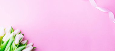 Anneler günü hediyesi. Bahar beyazı lale çiçeği, pembe arka planda kırmızı kurdeleli hediye. Sevgililer günü, doğum günü, kadınlar veya düğün günü konsepti