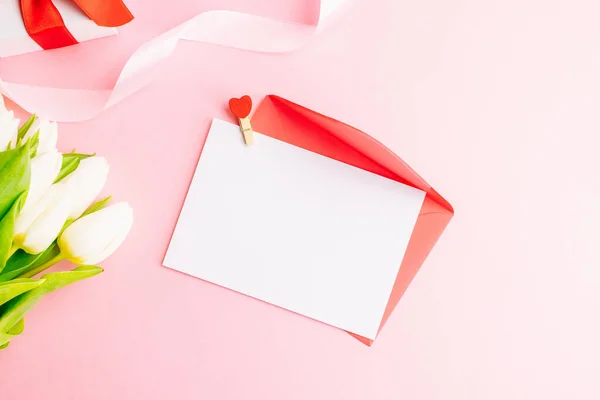 Moederdag achtergrond. Voorjaar witte tulp bloem, geschenkdoos met rood lint op platte lay roze achtergrond. Top view bruiloft liefde minimaal concept. — Stockfoto