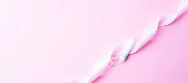 Tampons hygiène féminine. Ruban rose avec tampon menstruel sur fond rose. Concept d'hygiène sanitaire. Règles menstruelles féminines. Menstruation, jours critiques, zéro déchet, éco, bannière écologie. — Photo