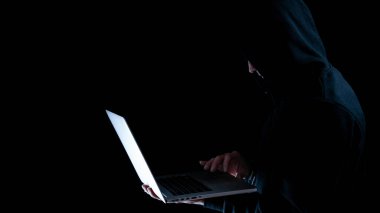 Siber güvenlik korsanı konsepti. İnternet hackleme teknolojisi. Bilgisayar korsanının elindeki dijital dizüstü bilgisayar siyah pankartta izole edilmiş. Veri koruması, güvenli internet erişimi, siber güvenlik