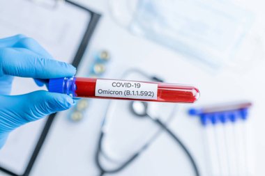 Omicron mutasyon koronavirüsü varyantı. Tıbbi laboratuvar doktoru hastane laboratuarında deney tüpü tutuyor. Pandemik önleme. Klinik araştırma