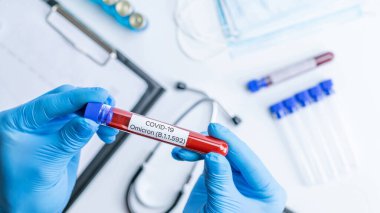 Omicron mutasyon koronavirüsü varyantı. Tıbbi laboratuvar doktoru hastane laboratuarında deney tüpü tutuyor. Pandemik önleme. Klinik araştırma