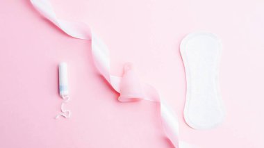 Adet bardağı, tampon, hijyenik koruma için kadın bardağı. Adet bardaklı pembe kurdele. Adet dönemi kadınsı. Sıfır atık kavramı, çevre dostu yaşam tarzı, düşük bayrak tüketimi