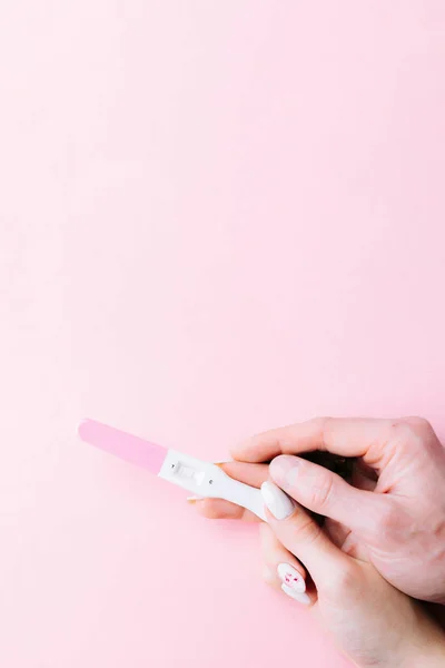 妊娠検査のカップル ピンクの背景にピンクのシルクリボンで手の中に肯定的な女性妊娠検査 新しい人生と新しい家族 出産管理の概念 — ストック写真