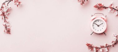 Bahar çiçeği. Çiçekler ve çiçekli pembe arka planda çalar saat. Yumuşak odaklı, çiçek açan kayısı makrosu dalları. Kopya alanı olan Paskalya tebrik kartları için. İlkbahar