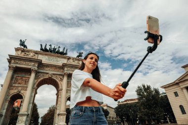 Gezginler Milan adasını etkiliyor. Avrupa 'da boyama evi Milano' da. Piazza del Duomo, Katedral Meydanı 'nda akıllı telefonlu fotoğrafçı kız. Seyahat ve serbest çalışma, modern yaşam tarzı.