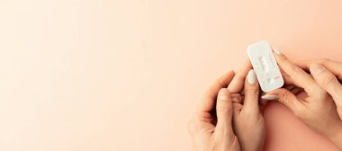 Hamilelik testi kiti. Kadın eli, pembe arka planda ipek kurdeleyle pozitif hamilelik testi yapıyor. Tıbbi sağlık, jinekoloji, gebelik, doğurganlık, doğum ve doğum insanları kavramı
