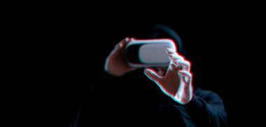 VR gözlükleri sanal gerçekliği maviye boyadı. Karanlık arka planda üç boyutlu sanal gerçeklik oyunu için dijital başlıklı genç adam. Hata efektli üç boyutlu simülasyonda çalışma ve sanal dünya