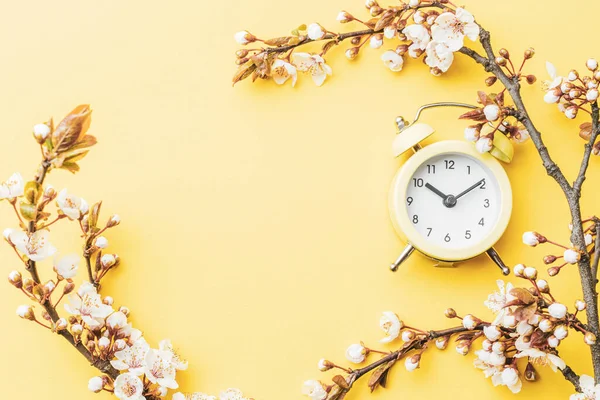 春の時間の背景 黄色の目覚まし時計と5月の花や4月の花の性質 柔らかい焦点を当てたアプリコットマクロの開花の枝 コピースペースとイースターグリーティングカードのために — ストック写真