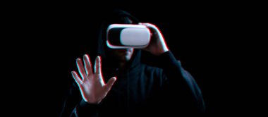 VR gözlükleri sanal gerçekliği maviye boyadı. Karanlık arka planda üç boyutlu sanal gerçeklik oyunu için dijital başlıklı genç adam. Hata efektli üç boyutlu simülasyonda çalışma ve sanal dünya