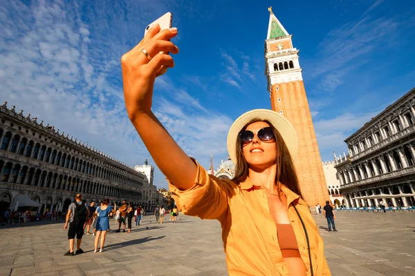 Travel blogger Venice italy. Photographer girl with smartphone in Venice San Marco square. Paint building house in travel Europe Venezia city. Hispter tourist using her phone outdoors
