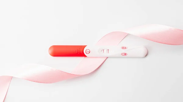 陽性の妊娠検査結果 白い背景にピンクのシルクリボンで女性妊娠検査 医療保健婦人科 妊娠不妊妊産婦の概念 — ストック写真