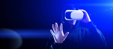 Sanal gerçeklik gözlükleri. Karanlık arka planda sanal gerçeklik teknolojisi için dijital kulaklık takan genç bir adam. İnanılmaz teknoloji, çevrimiçi oyun, eğlence