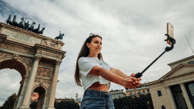 Gezginler Milan adasını etkiliyor. Avrupa 'da boyama evi Milano' da. Piazza del Duomo, Katedral Meydanı 'nda akıllı telefonlu fotoğrafçı kız. Seyahat ve serbest çalışma, modern yaşam tarzı.