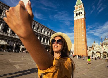 Seyahat etmenleri Venedik adasını etkiliyor. Avrupa 'da Venezia şehrinde boyama evi. Venice San Marco Meydanı 'nda akıllı telefonlu blogcu kız. Seyahat ve serbest çalışma, modern yaşam tarzı.